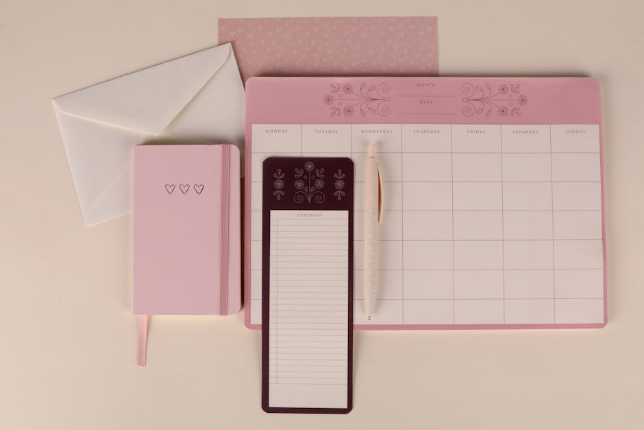 Elegant pink stationery flat lay with a planner, notebook, and checklist pad, perfect for organizing.