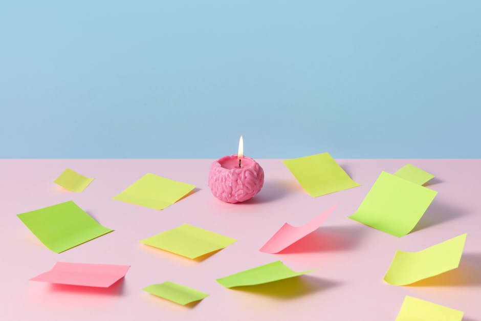 A pink brain candle lit among colorful sticky notes on pastel background, evoking creativity.
