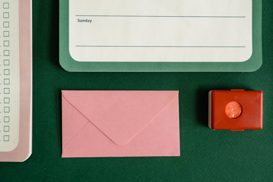 Flat lay of notepad, envelope, and stamp on a green surface.